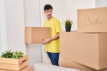Young caucasian man smiling confident holding package at new home