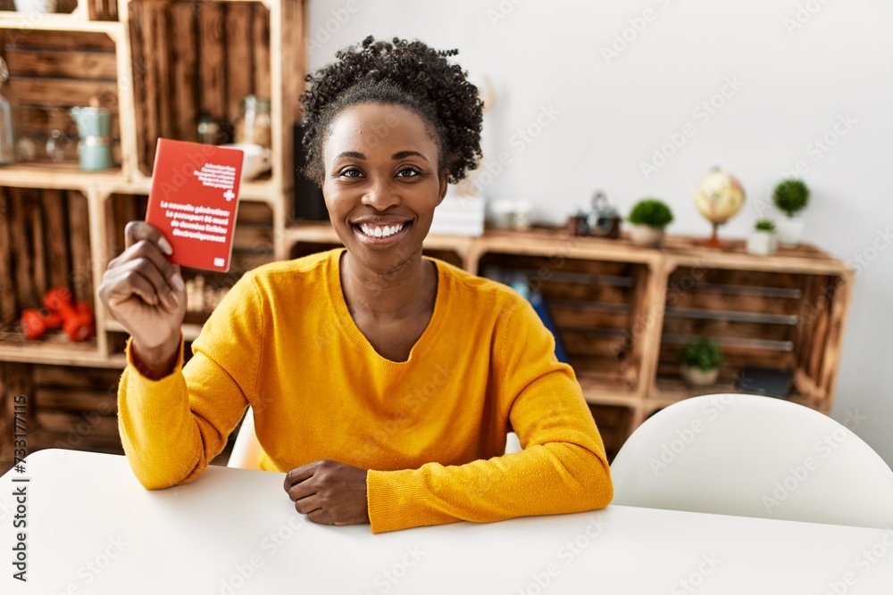 Wall mural african american woman holding switzerland passport sitting on table at home