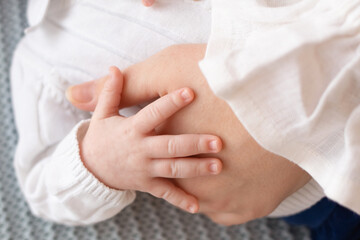 the parent's hand holds the little hand of the baby, close-up photo. family concept