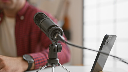 Young, handsome hispanic man masters the mic, live speak show at indoor radio studio, reporter professionally presenting news on air