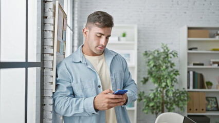 Young hispanic man business worker using smartphone at the office
