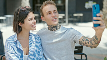 Beautiful coupler sitting together make selfie by smartphone at coffee shop terrace