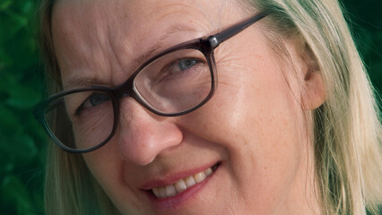 a woman with glasses smiling and looking at the camera