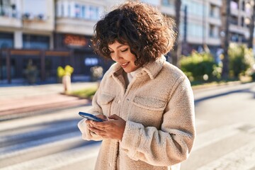 Young beautiful hispanic woman smiling confident using smartphone at street