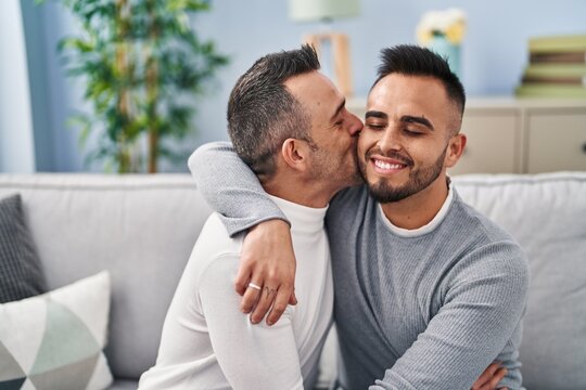 Two men couple hugging each other kissing at home