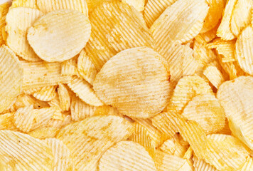 Top view of a full-frame background of crispy golden potato chips, perfect for snack or food themes.
