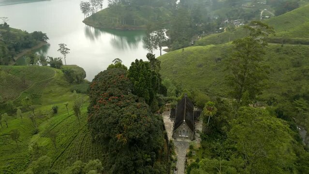 A colonial Christian Church on the hill by the lake among the patterned tea plantations. Highland nature landscape of Sri Lanka
