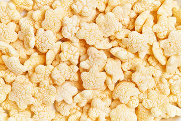 Close-up of yellow rice crisps filling the frame, representing snacks, diet, texture, and food background