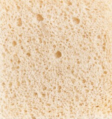 Close-up texture of a slice of white bread showcasing its porous structure and fine details.