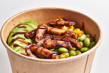 Close-up of a healthy grilled chicken salad with avocado, edamame, corn, and sauce in a takeaway bowl
