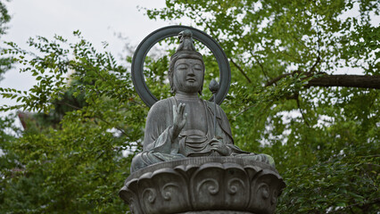 A serene buddha statue with a halo stands among lush greenery, symbolizing peace and spirituality.