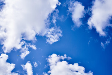 Obraz premium Vast blue sky adorned with fluffy white clouds and a distant tiny airplane soaring high.