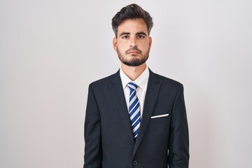 Young hispanic man with tattoos wearing business suit and tie relaxed with serious expression on face. simple and natural looking at the camera.