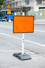 Blank sign mockup, ad template, metal orange board on pole, city background. Copy space. Vertical