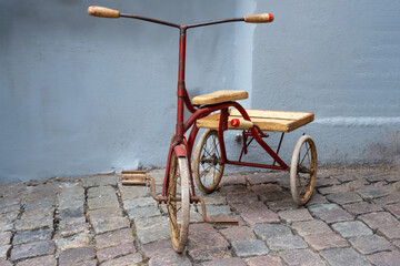 Three wheel vintage bike on stone paved path. 1940s retro-styled tricycle child wrought iron bicycle