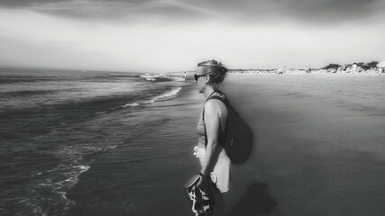 a woman walking on the beach with a surfboard - obrazy, fototapety, plakaty