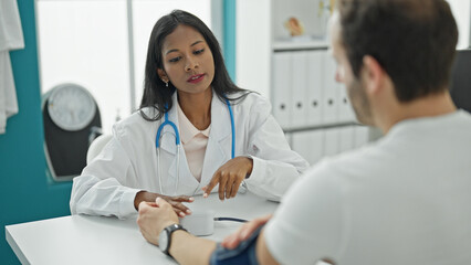 Fototapeta premium Doctor and patient sitting on table measuring pulse using tensiometer at the clinic