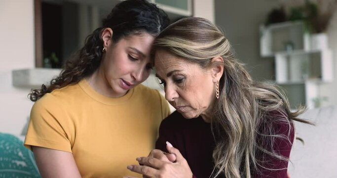 Loving young adult daughter stroking unhappy mature mother, comforting her, provide support after bad news, is near in hard period of life, giving care and love. Divorce, incurable disease, disorder