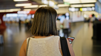 Young beautiful hispanic woman going on a trip using smartphone at the airport