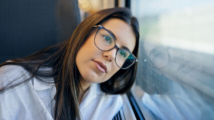 Young beautiful hispanic woman thinking looking through the window inside train wagon