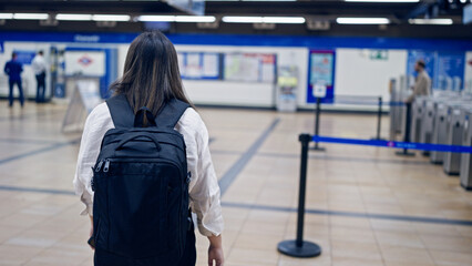 Young beautiful hispanic woman walking wearing backpack in subway station of Madrid