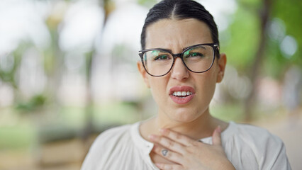 Young beautiful hispanic woman with sore throat at the park