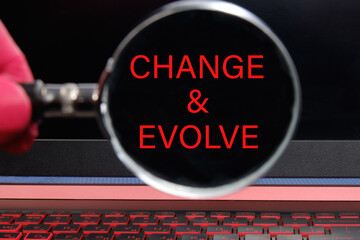 The text CHANGE EVOLVE written through a magnifying glass on a black laptop screen