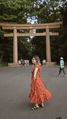 Joyful hispanic woman smiling with open arms, looking around at meiji temple, showcasing confidence and happiness