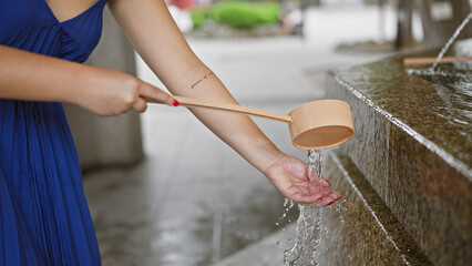 Young woman immersed in traditional ritual, washing hands in purifying cleanse at senso-ji temple,...