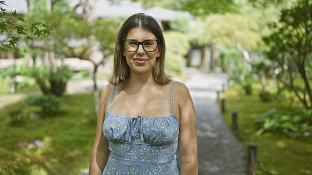 Beautiful hispanic woman in glasses, joyful portrait of her smiling, laughing and posing confident in japan's traditional kyoto park, emotion painted on her carefree face surrounded by nature