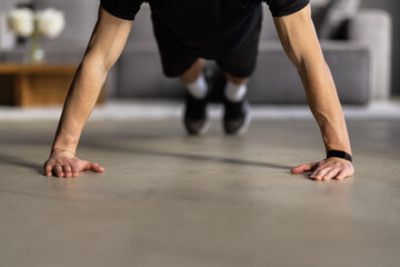 Young man looking at smartphone and doing plank exercise at home