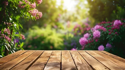 Tuinposter closeup wooden table with a blurred background of green garden and flower backdrop © Exsinghas