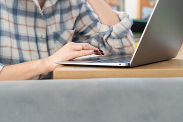 Close-up shot of a woman's hand working on a laptop keyboard. Concept of distance work, online learning and internet surfing