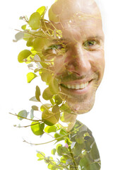 A double exposure portrait of a smiling man with green foliage - 733208728