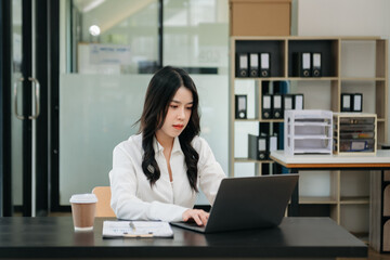 Asian businesswoman working in the office with working notepad, tablet and laptop documents .