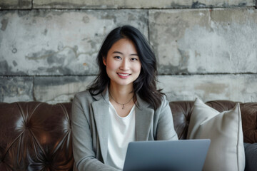 Happy smiling asian woman working on laptop computer while sitting on the floor.