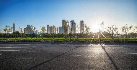 Sunrise Over Cityscape with Long Shadows on Empty Road