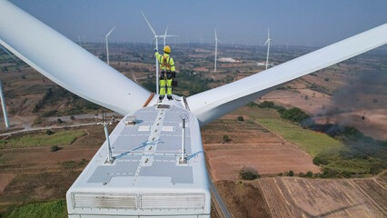 Wind mill engineer wearing PPE standing on wind turbine.  engineer feel success after good work. He standing a top of wind mill.