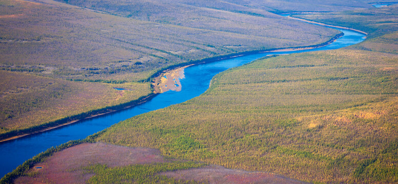 Top view of the autumn Siberian taiga and the Tunguska River with its tributary.