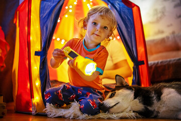 Obraz na płótnie Canvas Child with Flashlight in Play Tent with Dog