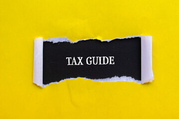Tax guide words written on torn yellow paper with black background. Conceptual business symbol....
