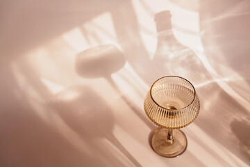 Two glasses with white wine placed on light beige background with shadows and fantastic highlights...
