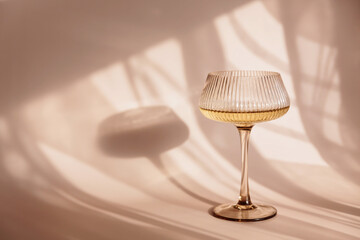 Glass with white wine placed on light background with shadows and fantastic highlights and...