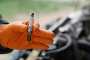 Obraz premium Close up mechanic hand hold old spark plug, spare part of car engine. Concept, machine maintenance, fix, repair, check or diagnose automobile problems by engine specialist. 