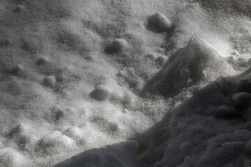 View of snow and shadow. White snow on a sunny day and gray shadow. Irregularities on white snow,...