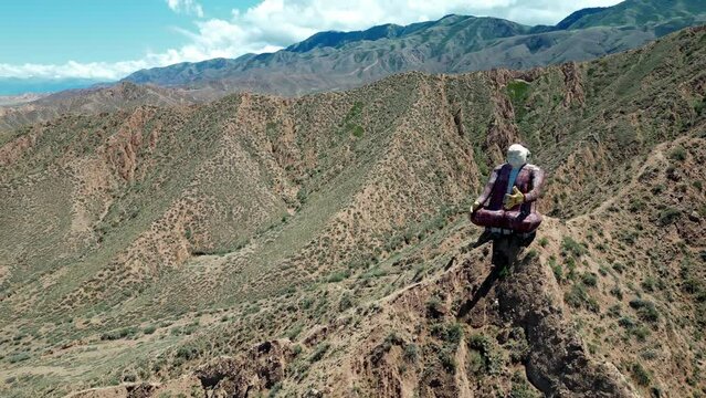 Aerial, Flight around monument to real personality, best storyteller Kyrgyz epic Manas, Sayakbai Karalaev. Aalam Ordo complex, coast of southern shore Issyk Kul lake, Kyrgyzstan. Memorial on mountain