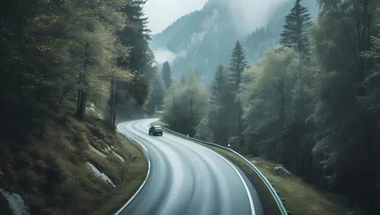 Fotobehang a car is driving down a winding road in a mountainside forest © Asep
