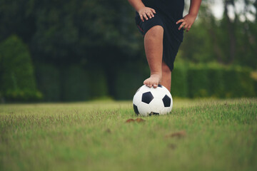 Little boy feet holding football at grass field