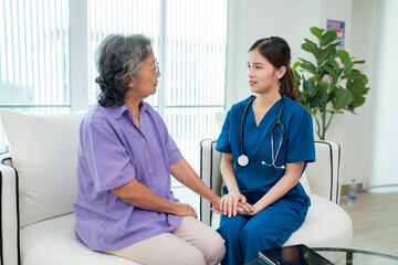 Obraz premium Asian female doctor taking care and talking mature female patient sitting on sofa in hospital. Healthcare concept.