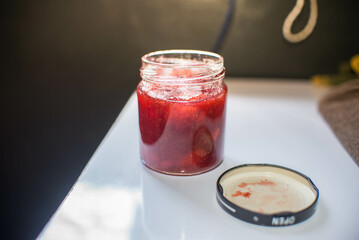 Strawberry jam opened on a white table